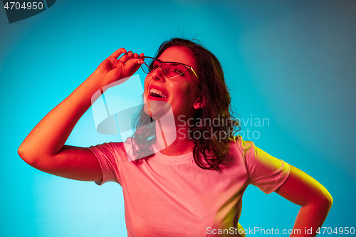 Image of Happy young woman standing and smiling against blue background