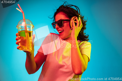 Image of Happy young woman standing and smiling against blue background