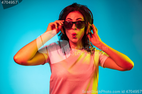 Image of Happy young woman standing and smiling against blue background