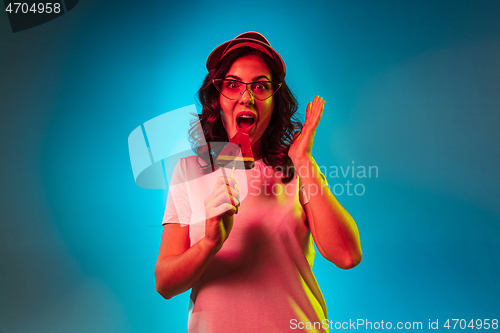 Image of Happy young woman standing and smiling against blue background