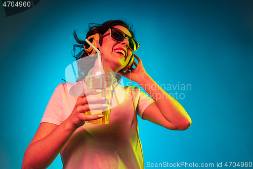 Image of Happy young woman standing and smiling against blue background