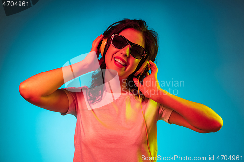 Image of Happy young woman standing and smiling against blue background