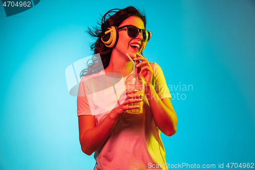 Image of Happy young woman standing and smiling against blue background