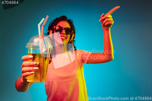 Image of Happy young woman standing and smiling against blue background