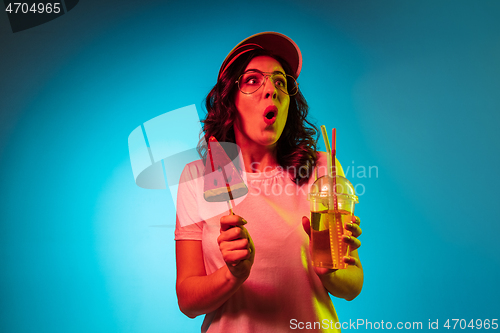 Image of Happy young woman standing and smiling against blue background