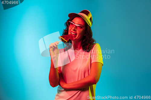 Image of Happy young woman standing and smiling against blue background