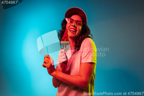 Image of Happy young woman standing and smiling against blue background