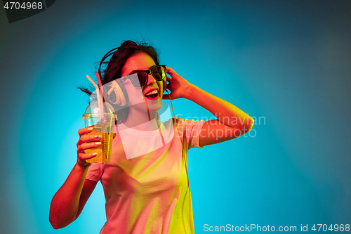 Image of Happy young woman standing and smiling against blue background