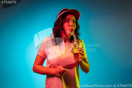 Image of Happy young woman standing and smiling against blue background