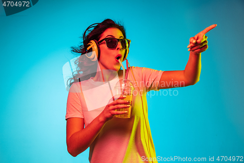 Image of Happy young woman standing and smiling against blue background