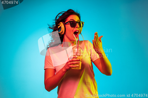 Image of Happy young woman standing and smiling against blue background