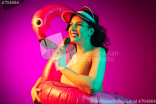 Image of Happy young woman standing and smiling against pink background