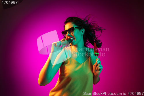 Image of Happy young woman standing and smiling against pink background