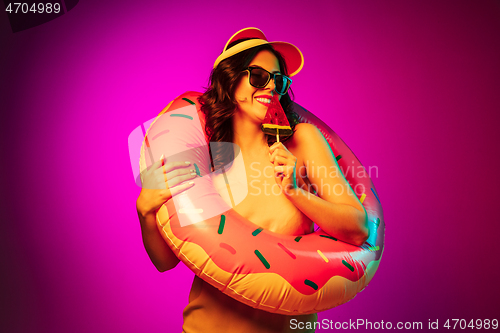 Image of Happy young woman standing and smiling against pink background