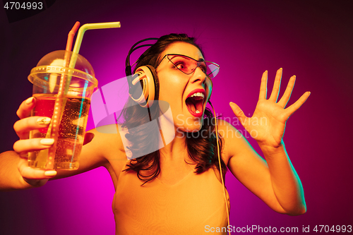 Image of Happy young woman standing and smiling against pink background