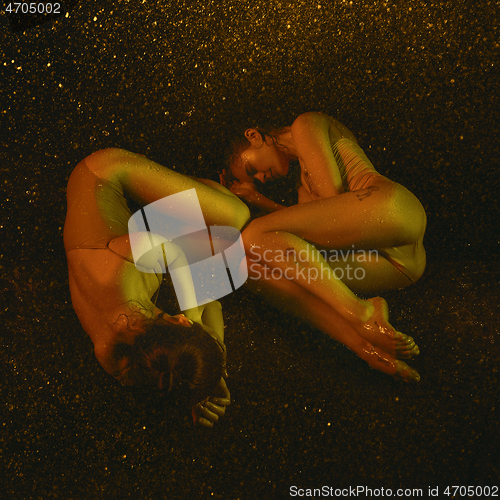 Image of Two young female ballet dancers under water drops