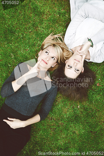 Image of Two thoughtful girls lying in the grass