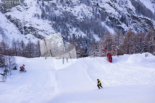 Image of rescue team with a red helicopter rescuing a hurt skier