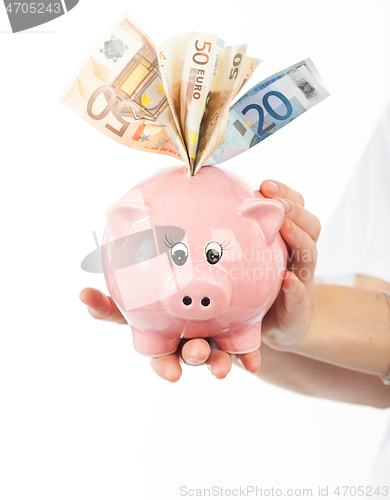 Image of A woman shows a piggy bank full of European banknotes