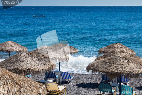 Image of beach with umbrellas and deck chairs by the sea in Santorini