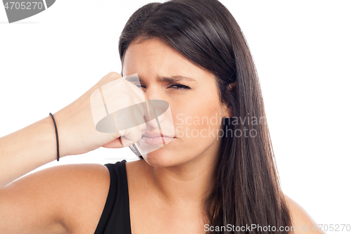 Image of portrait of a brunette woman pinching her nose because of a bad 