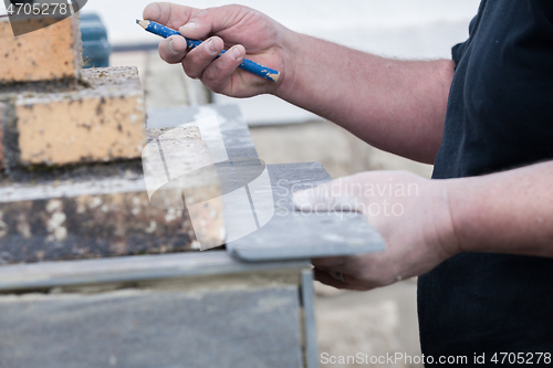 Image of the tiler measures and puts marks to cut and lay a tile