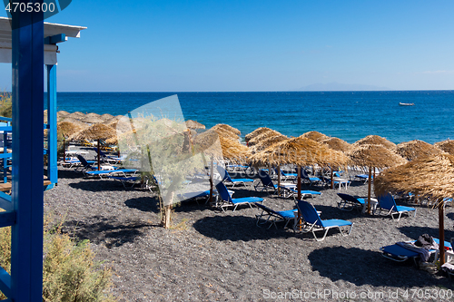 Image of beach with umbrellas and deck chairs by the sea in Santorini