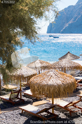 Image of beach with umbrellas and deck chairs by the sea in Santorini