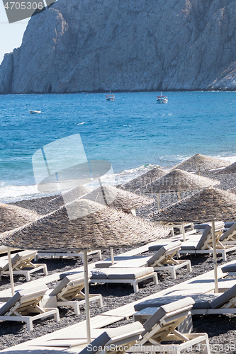 Image of beach with umbrellas and deck chairs by the sea in Santorini