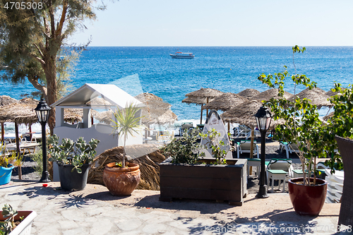 Image of beach with umbrellas and deck chairs by the sea in Santorini