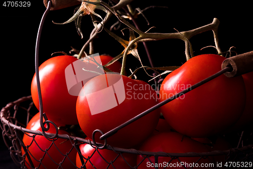 Image of big red tomatoes on black background in light dark ready to cook