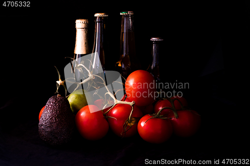 Image of large red and ripe tomatoes with lime avocado and bottle of beer