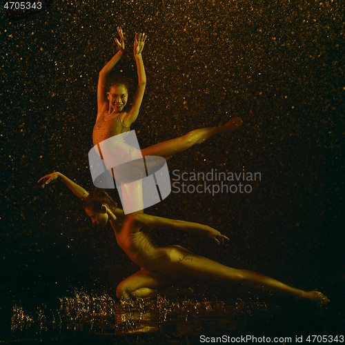 Image of Two young female ballet dancers under water drops