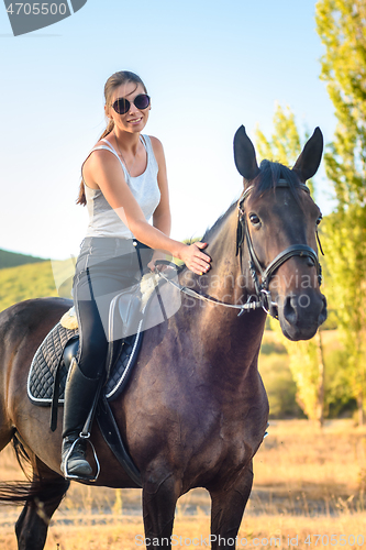 Image of Beautiful slender pretty girl sitting on a horse, close-up
