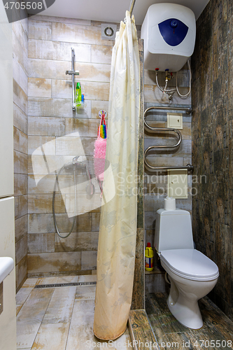 Image of Small compact bathroom divided with shower curtain and toilet