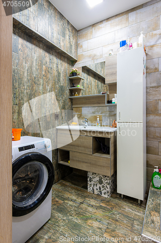 Image of Interior of a cozy compact modern bathroom with a washing machine