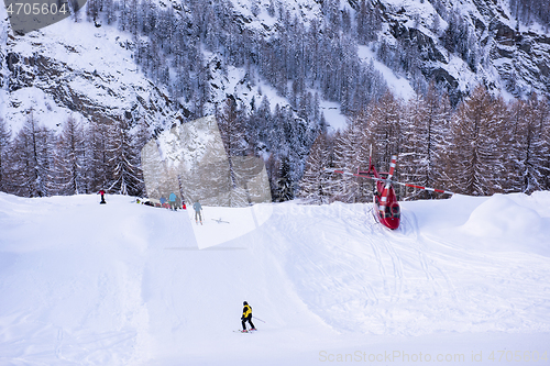 Image of rescue team with a red helicopter rescuing a hurt skier