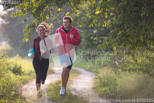 Image of young couple jogging along a country road