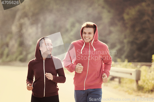Image of young couple jogging along a country road