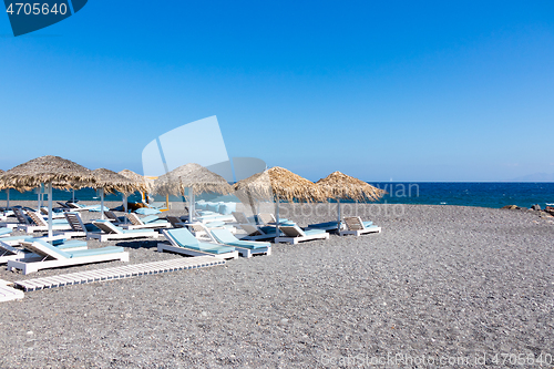 Image of beach with umbrellas and deck chairs by the sea in Santorini