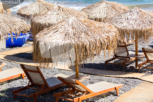 Image of beach with umbrellas and deck chairs by the sea in Santorini