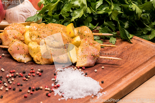 Image of raw chicken skewers marinated with lemon on a wooden board