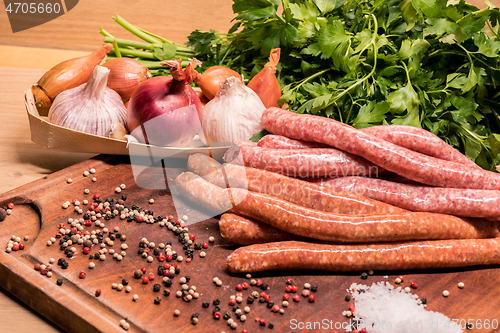 Image of raw sausages with chilli and herbs on a wooden board with spices