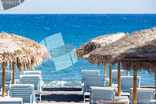 Image of beach with umbrellas and deck chairs by the sea in Santorini