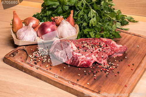 Image of steak of beef on a wooden board with spices pepper parsley salt 