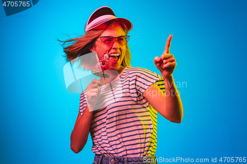 Image of Beautiful woman in neon light isolated on blue studio background