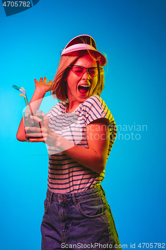 Image of Beautiful woman in neon light isolated on blue studio background