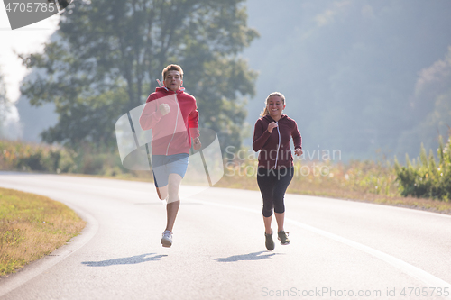 Image of young couple jogging along a country road