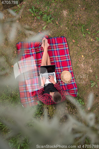 Image of top view of man using a laptop computer under the tree