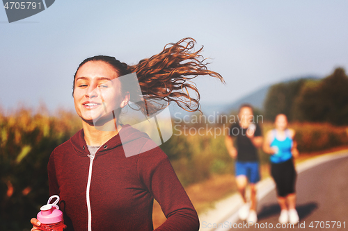 Image of young people jogging on country road